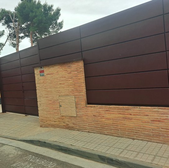 Detalle del portón reforzado con chapa metálica galvanizada y cerradura multipunto