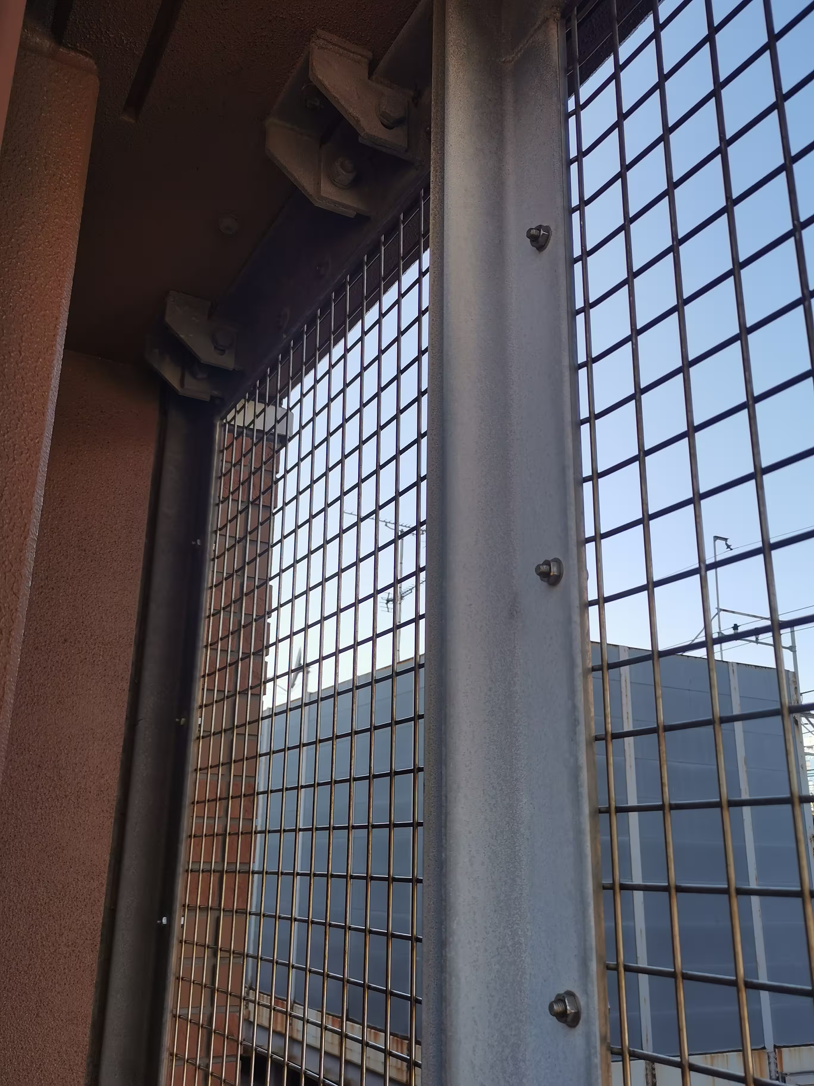 Detalle de fijación doble abrazando el marco de la rejilla con tornillería galvanizada