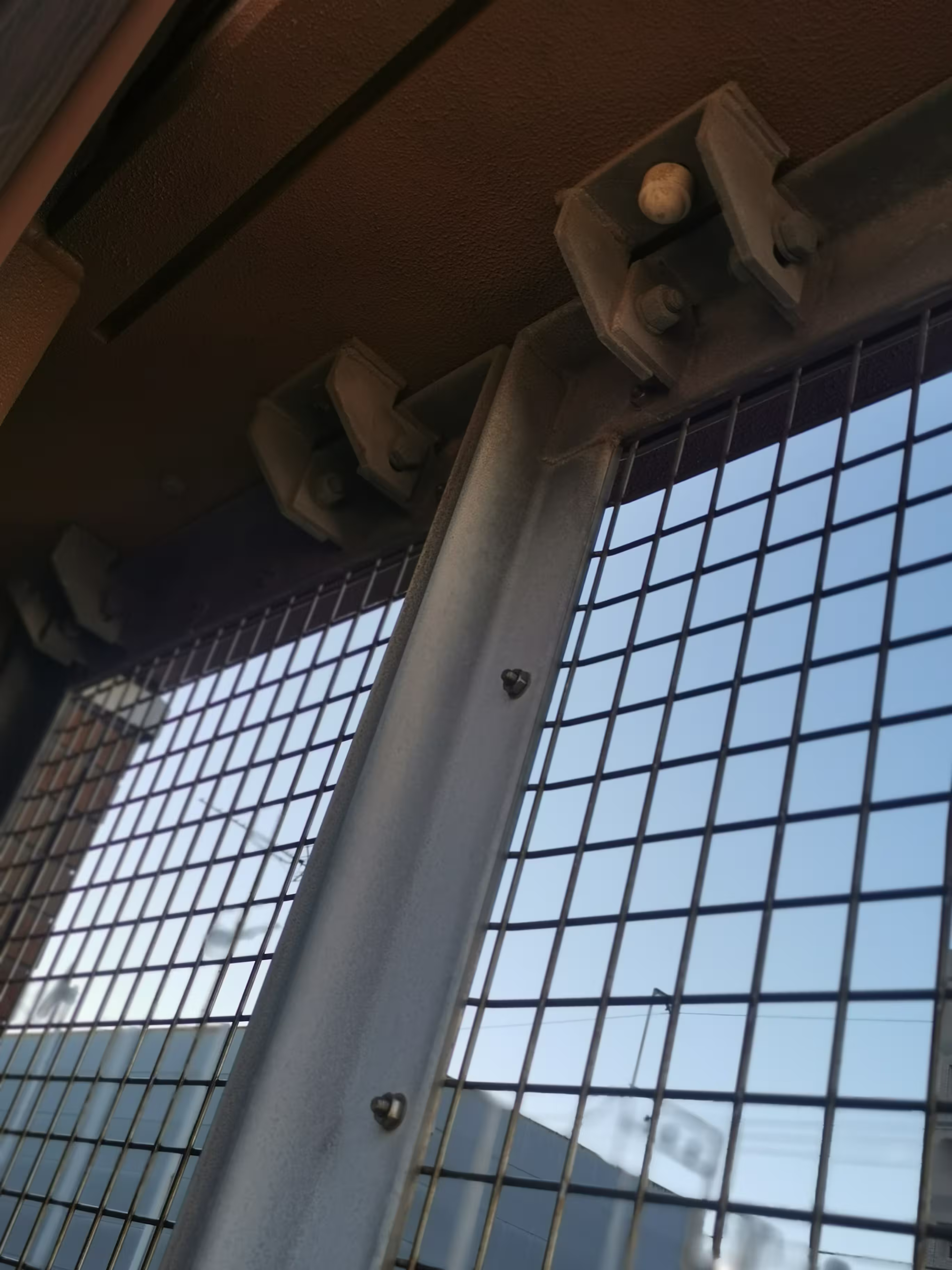 Fijación superior de rejilla con escuadra metálica atornillada a estructura existente